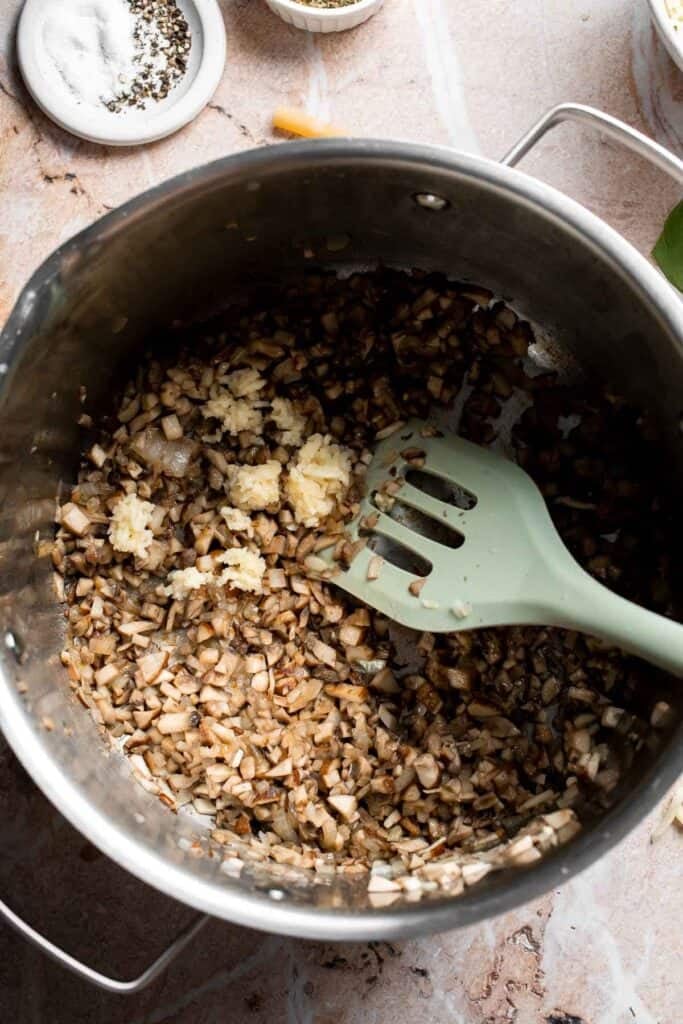 Adding garlic to cooked mushroom and onion mixture with most of the moisture evaporated in a pot