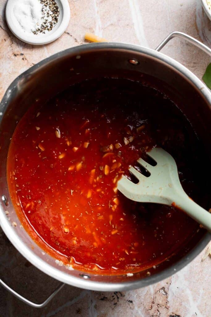 Marinara sauce simmering in a pot with a spatula