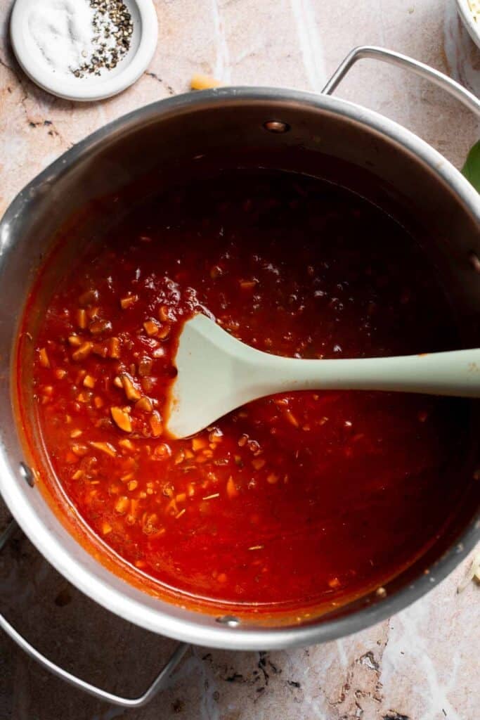 Marinara sauce being stirred with a spatula in a pot