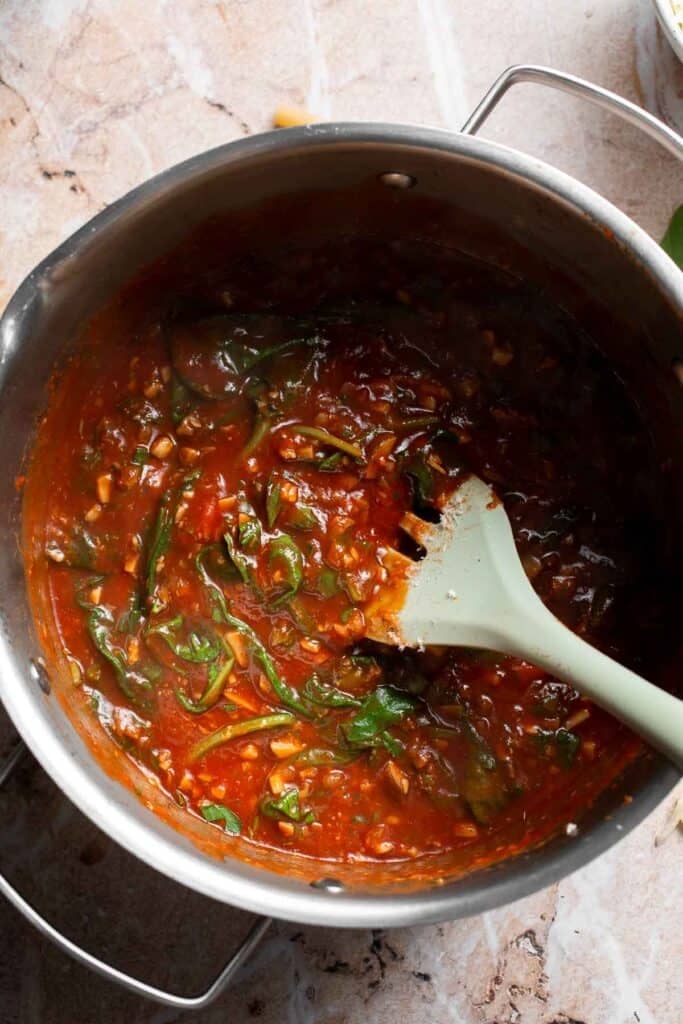 Marinara sauce simmering with parsley and basil stirred in