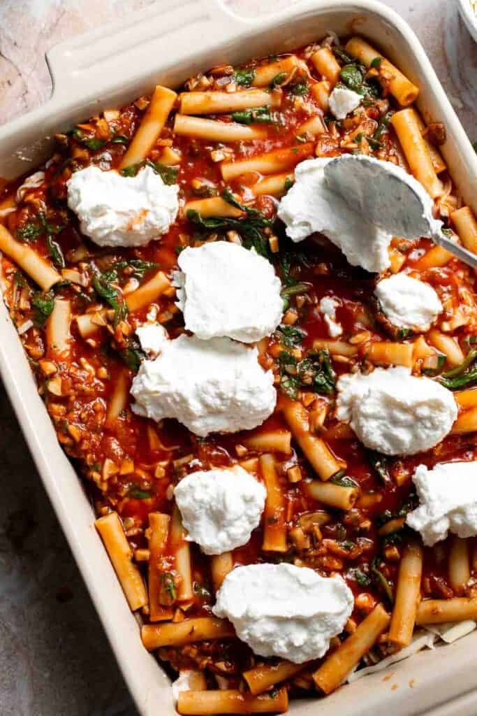 Dollops of ricotta mixture added over the second pasta layer in a baking dish