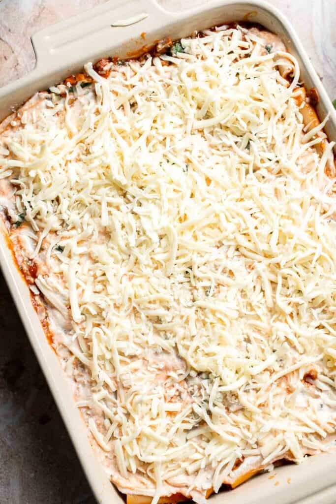 Shredded mozzarella cheese covering the top layer of unbaked ziti