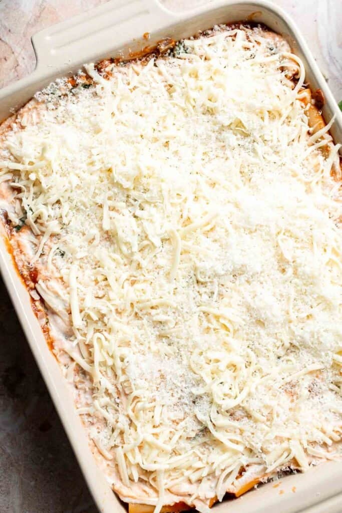 Unbaked vegetarian baked ziti topped with shredded mozzarella and Parmesan