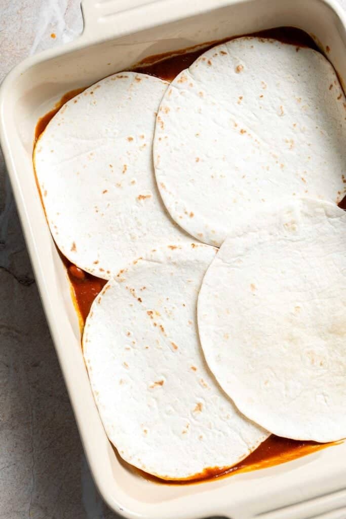 Tortillas overlapping to cover the bottom of a casserole dish