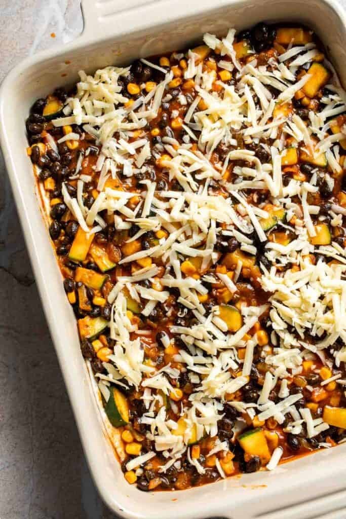 Shredded cheese sprinkled over a layer of filling in a casserole dish