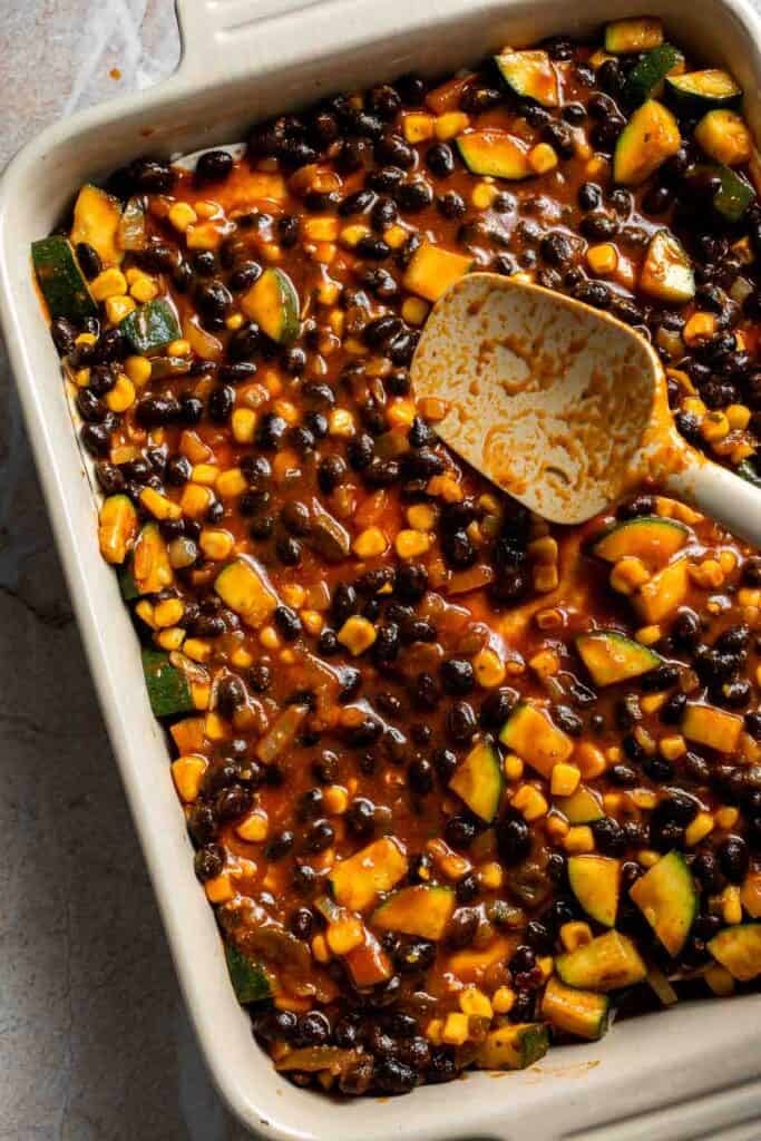 Vegetable filling spread over the second tortilla layer in a casserole dish