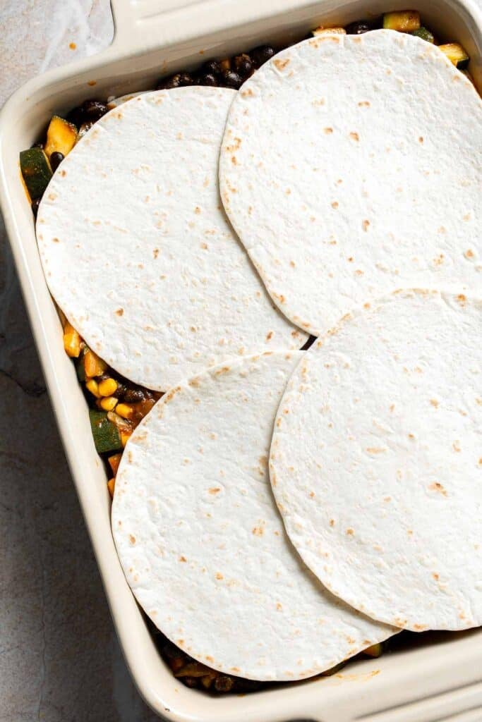 A final layer of tortillas being added to a casserole dish