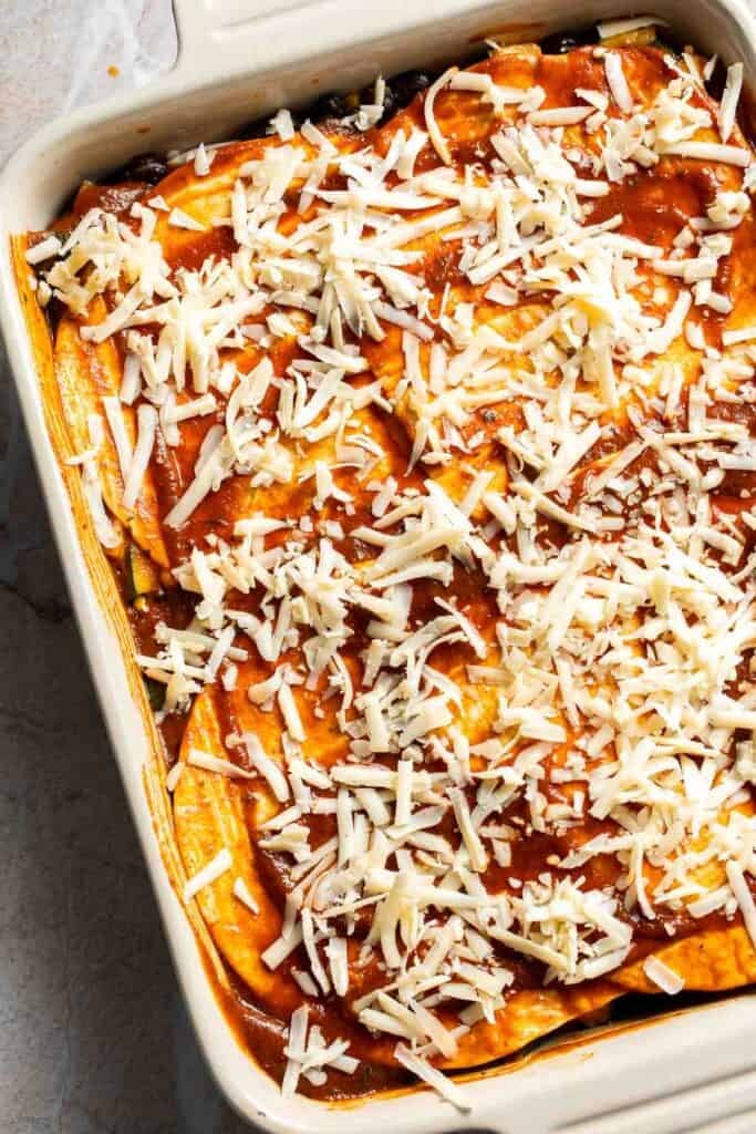 Shredded cheese sprinkled over the top of an unbaked enchilada casserole