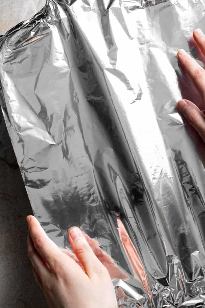 Aluminum foil being placed over a casserole dish before baking