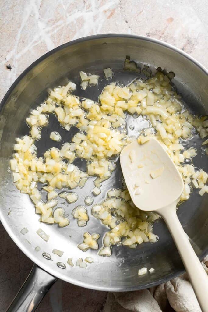 Diced onion sautéing in a skillet with a spatula