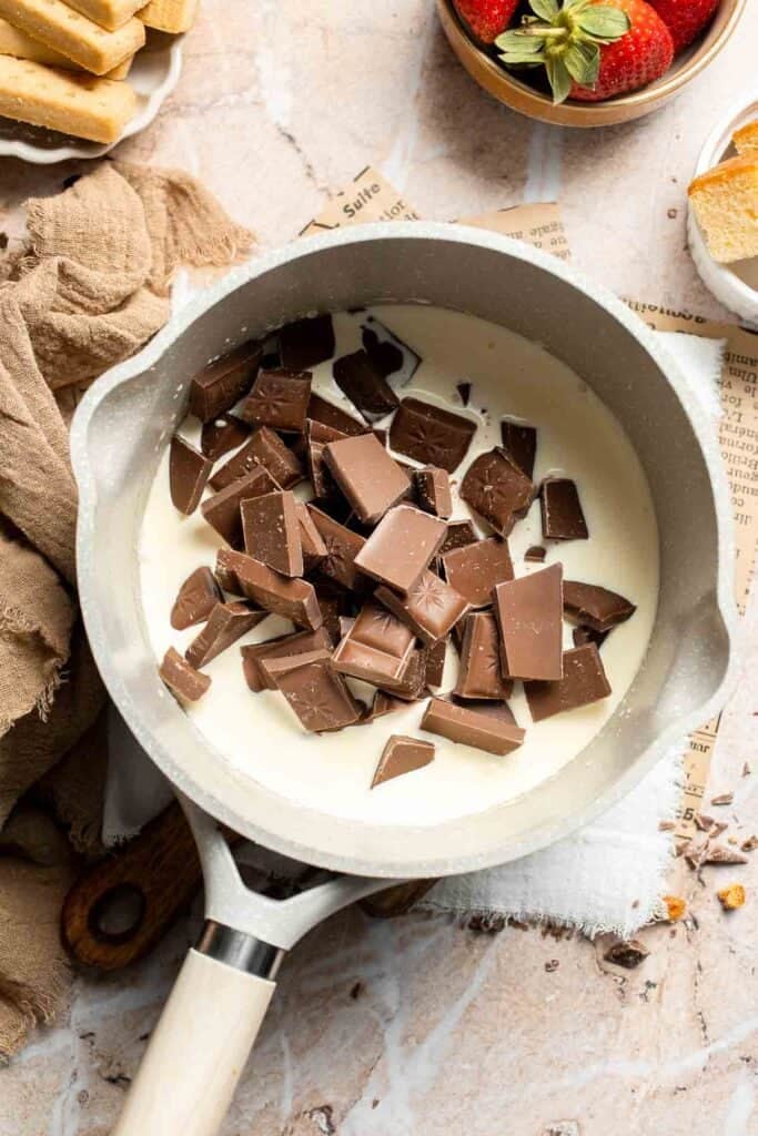 Chopped chocolate pieces resting in the warm cream before melting.