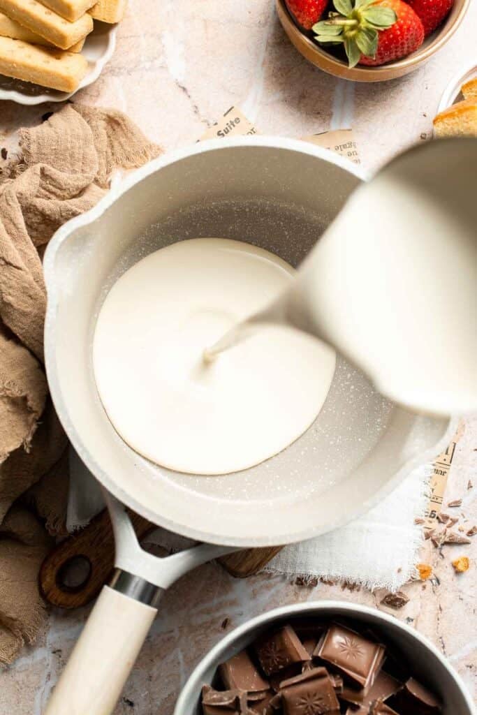 Pouring heavy cream into a small saucepan.