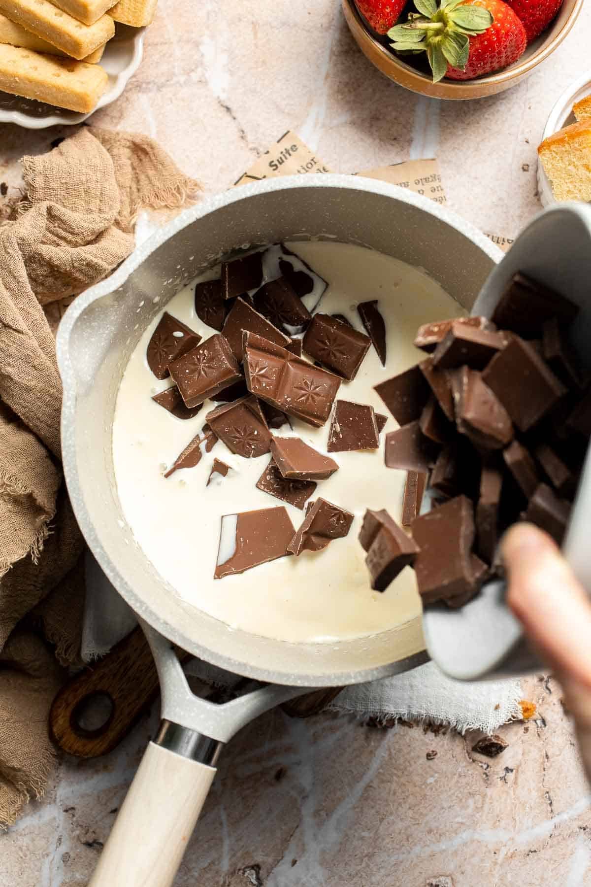 Adding chopped semisweet chocolate to the warm cream in the saucepan.