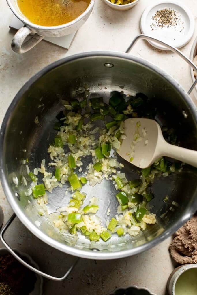 Stirring the garlic, onion, and peppers together until fragrant.