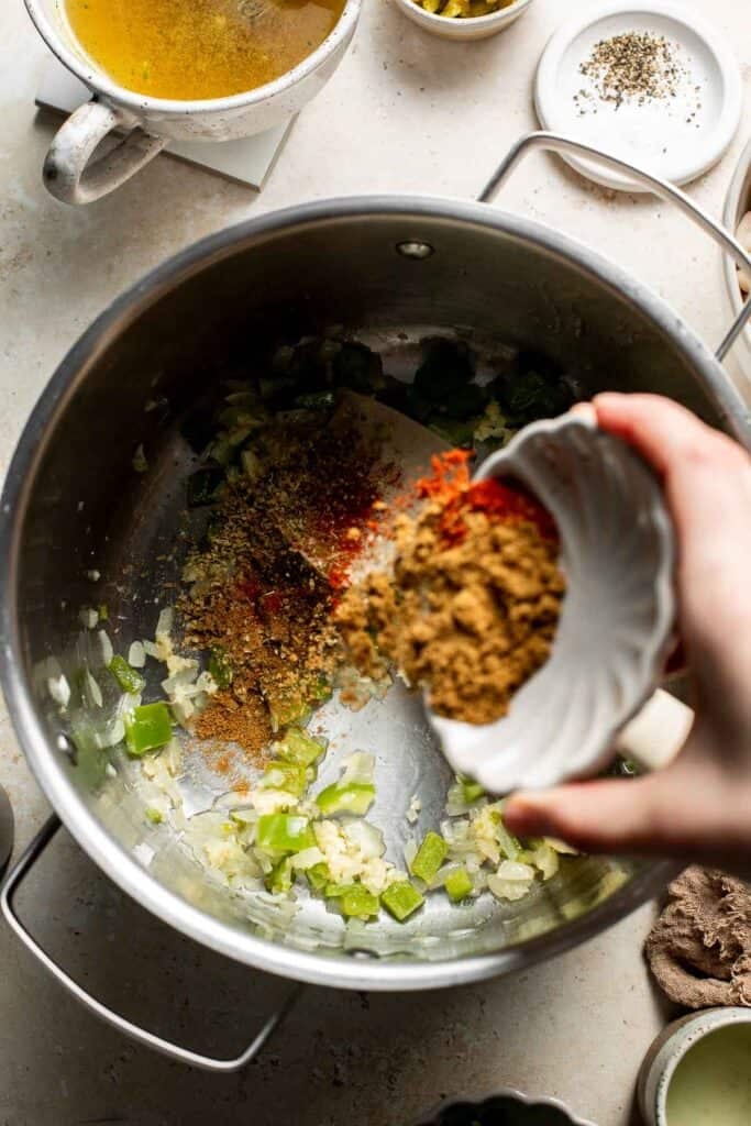 Adding cumin, oregano, and smoked paprika to the vegetables in the pot.
