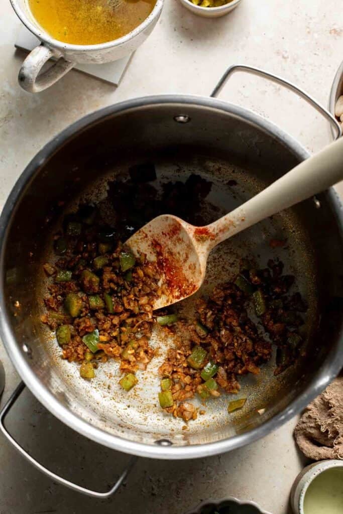Stirring the toasted spices and vegetables in the pot.