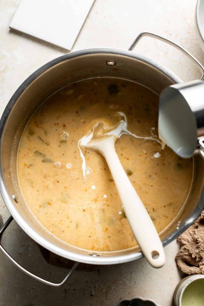 Pouring heavy cream into the pot of chili.