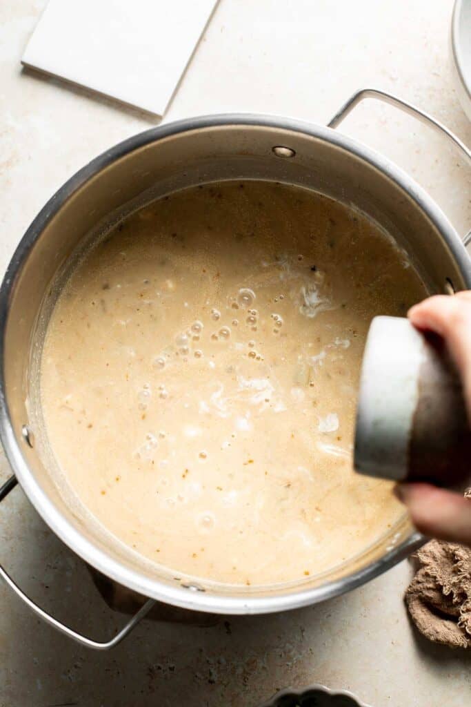 Pouring lime juice into the creamy chili in the pot.