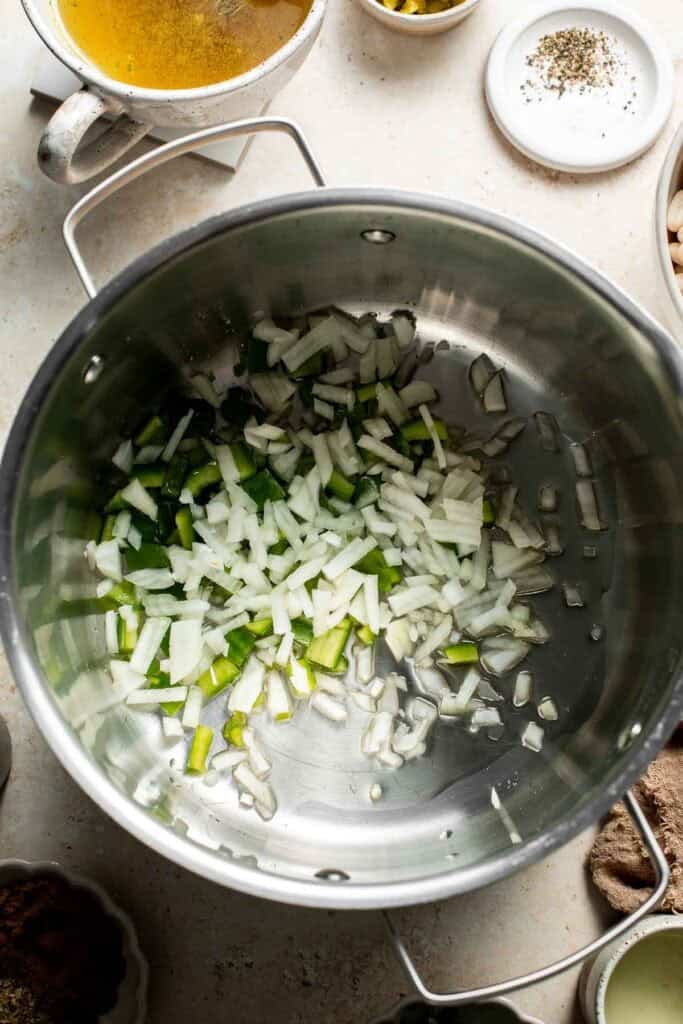 Diced onion and green peppers in a stainless steel pot, ready to cook.