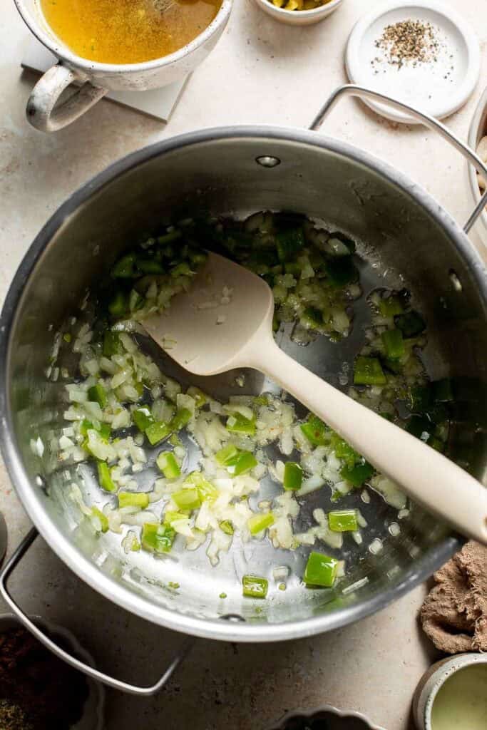 Stirring the softened onion and peppers in the pot with a spatula.