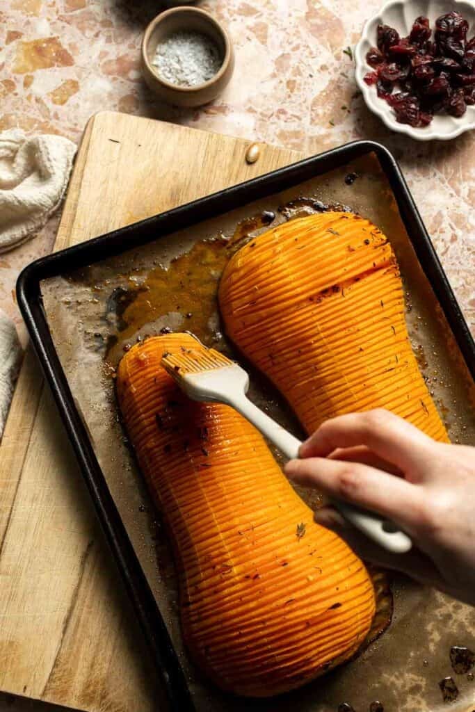 Brushing pan juices and maple butter between the slices of the roasting squash.