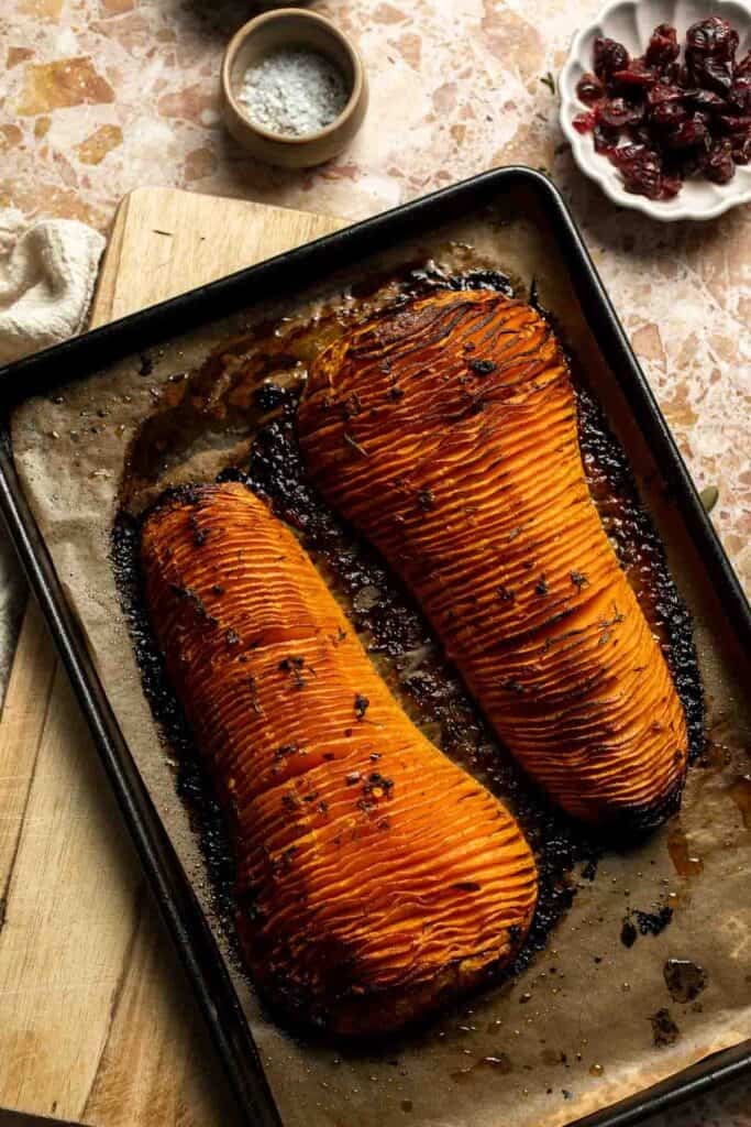 Fully roasted hasselback butternut squash with deeply caramelized, browned edges on the baking sheet.