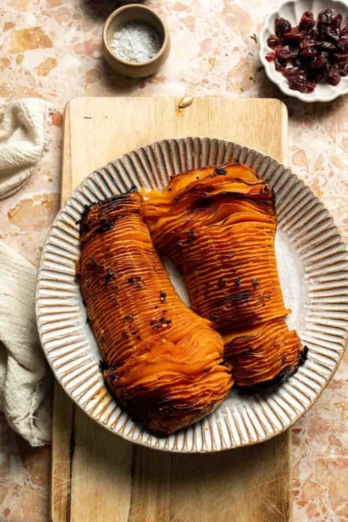Roasted hasselback butternut squash on a striped serving platter.