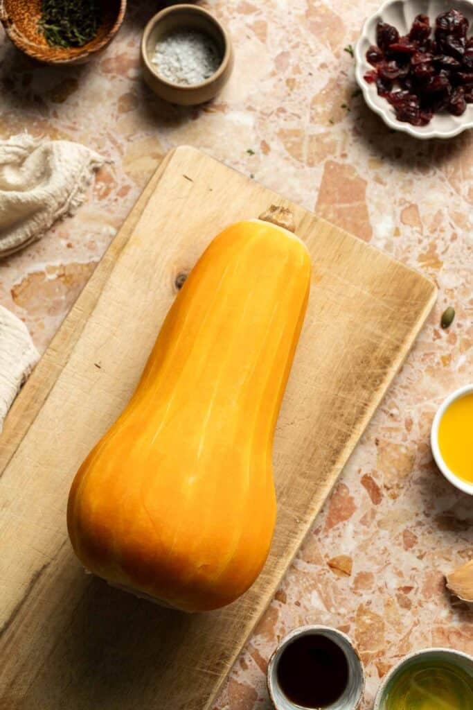 Peeled butternut squash on a wooden cutting board.