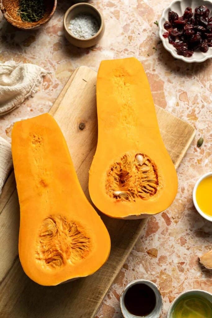 Peeled butternut squash cut in half lengthwise, showing the seeds in the bulb.