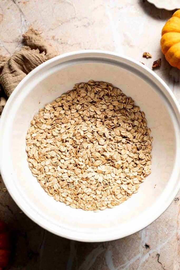 Dry oat and spice mixture in a large white mixing bowl, ready for the wet ingredients