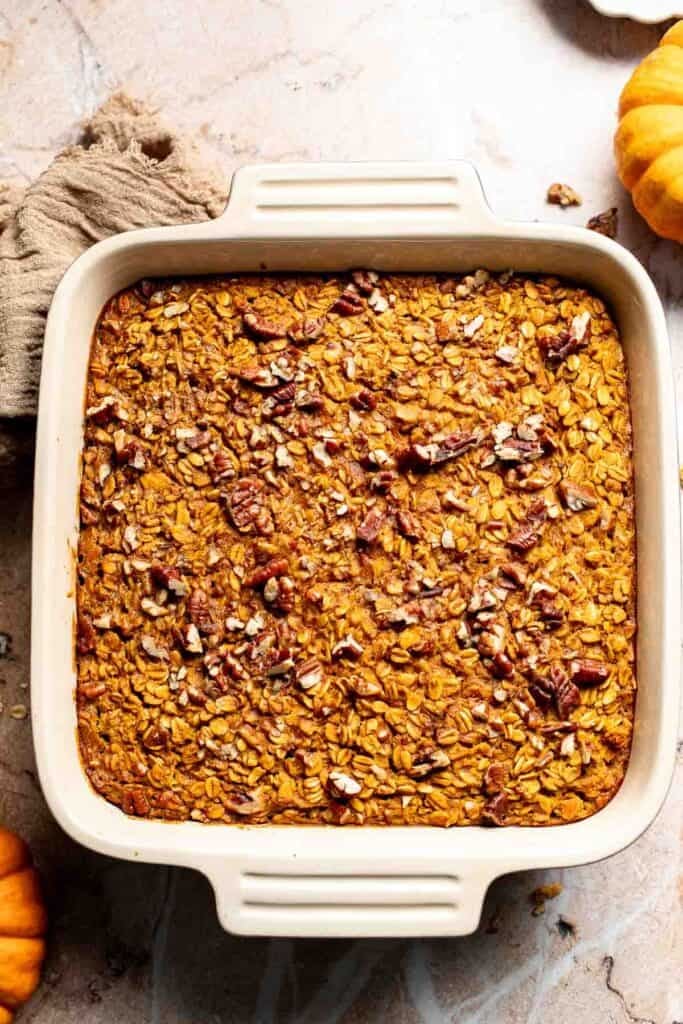 Baked pumpkin oatmeal with golden edges and toasted pecans in a baking dish