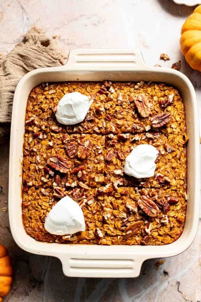 Pumpkin baked oatmeal with Greek yogurt and pecans on top in a baking dish