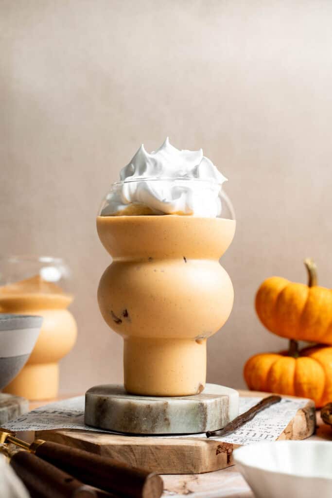 Pumpkin pie smoothie in a stacked glass topped with whipped cream.