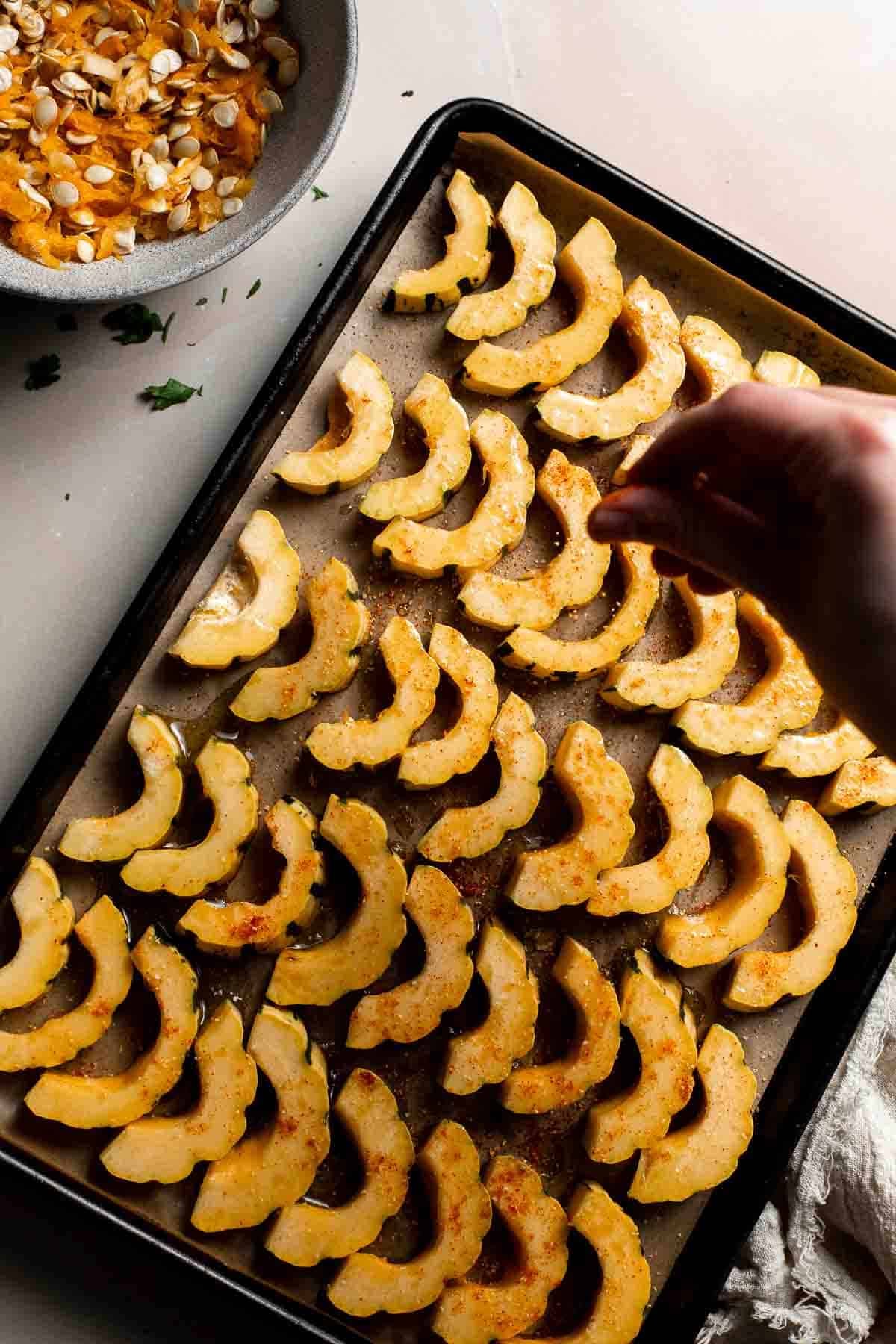 Sprinkling smoked paprika and garlic powder over the delicata squash slices.