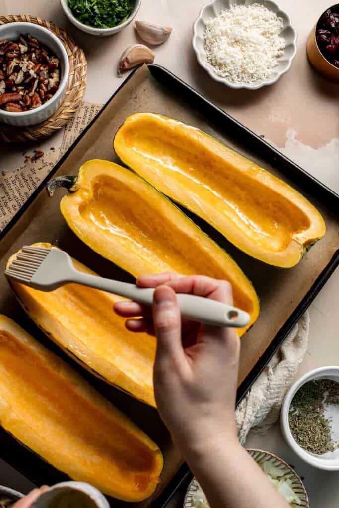 Brushing olive oil over the delicata squash halves.