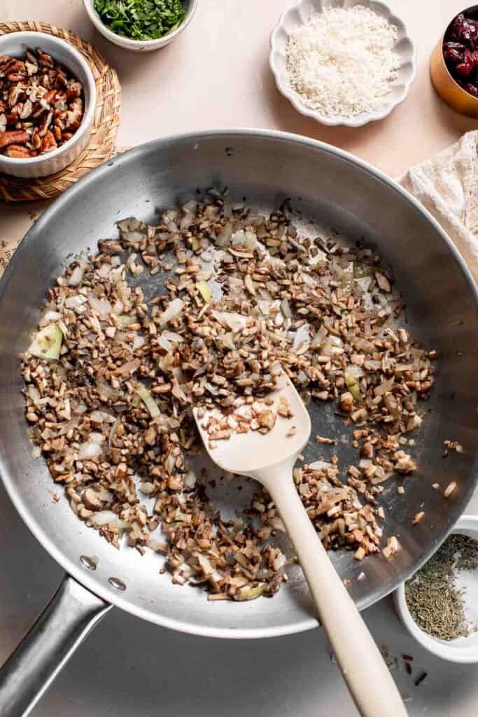 Stirring the mushrooms and onion as they cook down in the skillet.
