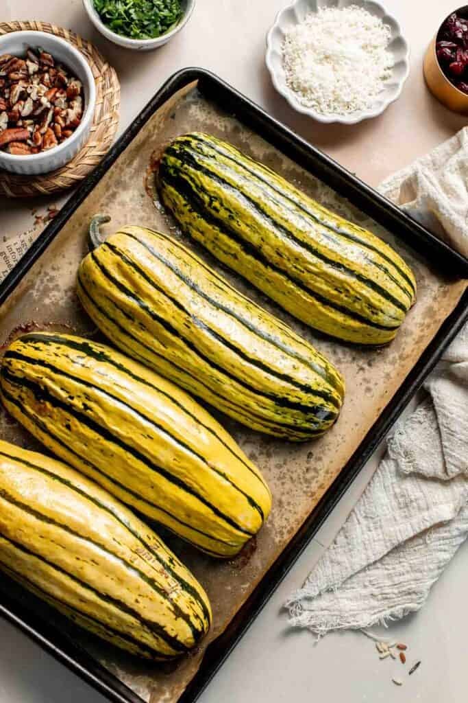 Roasted delicata squash on a baking sheet, golden and tender.
