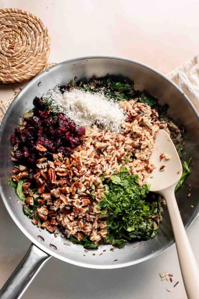Cooked wild rice, dried cranberries, pecans, Parmesan, and parsley added to the skillet of vegetables.