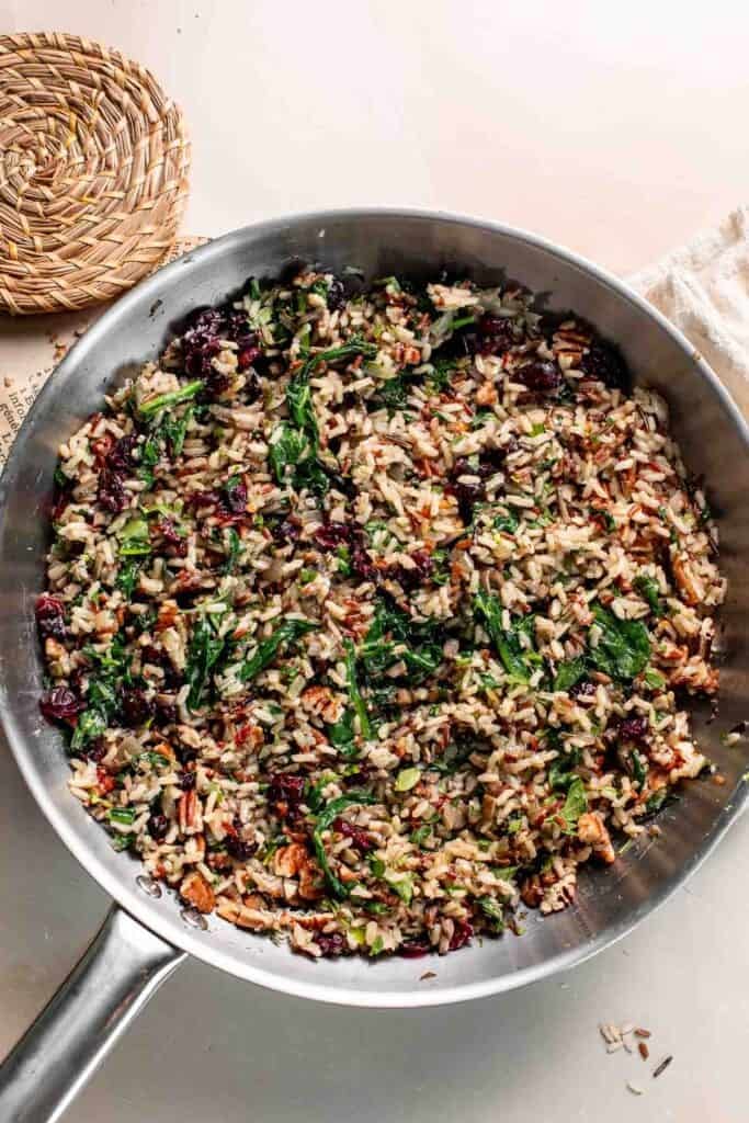 Finished wild rice filling with mushrooms, spinach, cranberries, and pecans in the skillet.