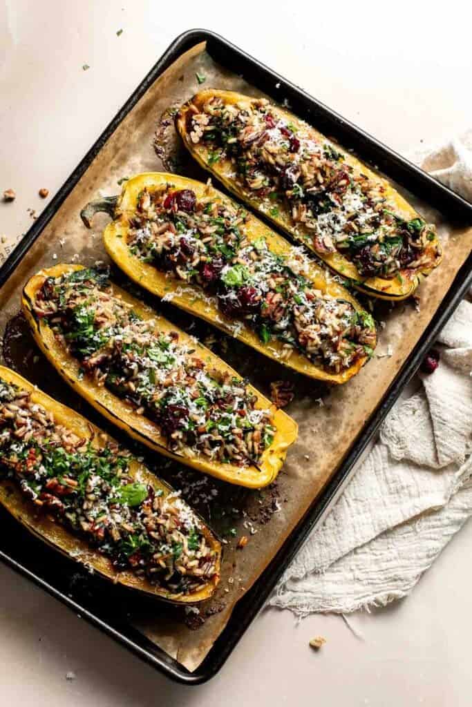 Stuffed delicata squash halves topped with Parmesan before the final bake.