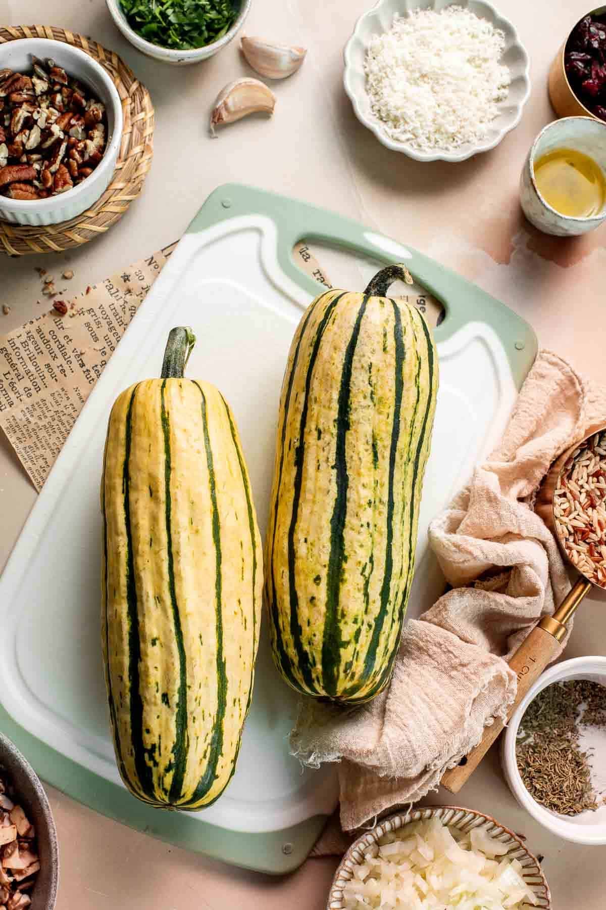 Two whole delicata squash on a green cutting board.