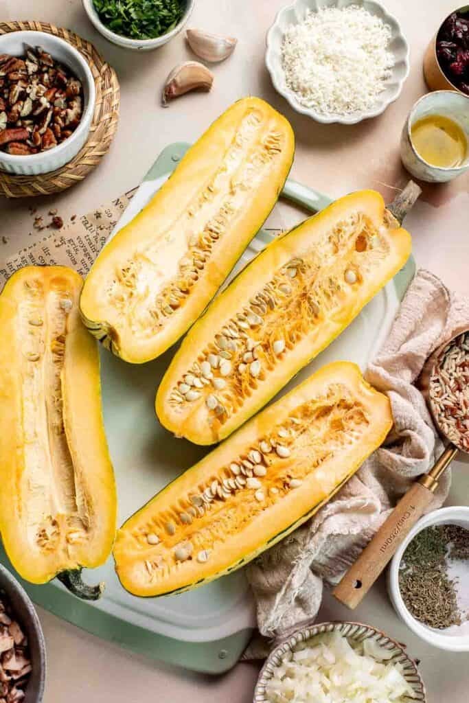 Delicata squash cut in half lengthwise, showing the seeds and stringy flesh inside.