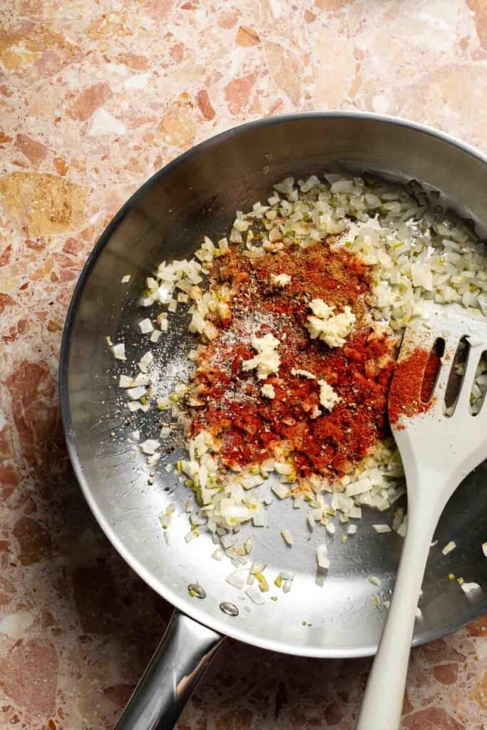 Adding garlic on top of the spices, sautéed onion, and jalapeño before stirring.