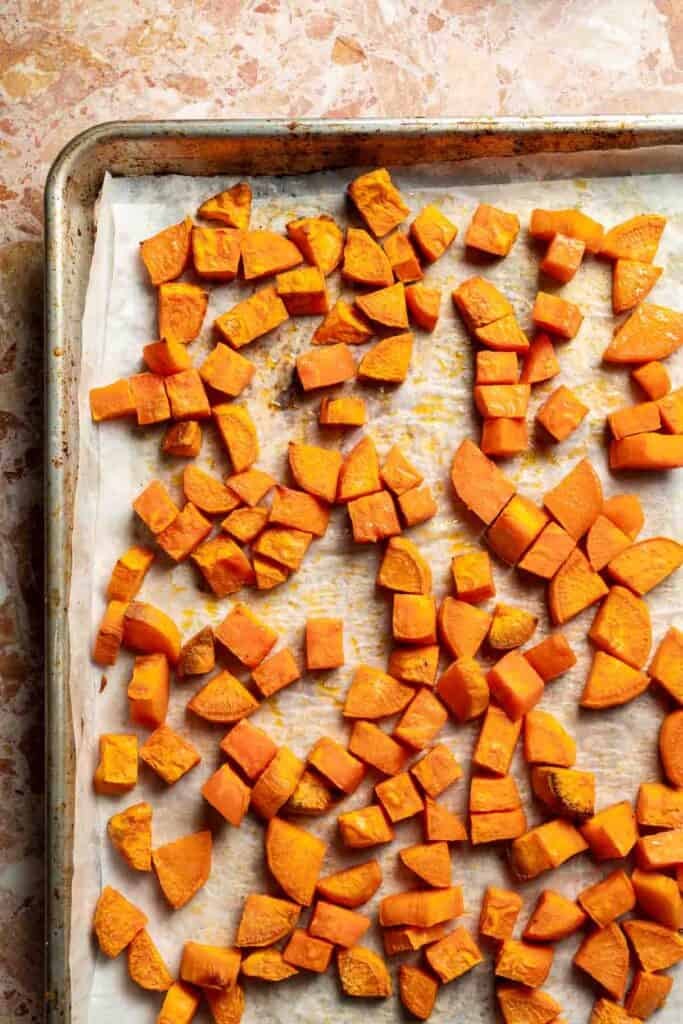 Roasted sweet potatoes lightly caramelized on the baking sheet.