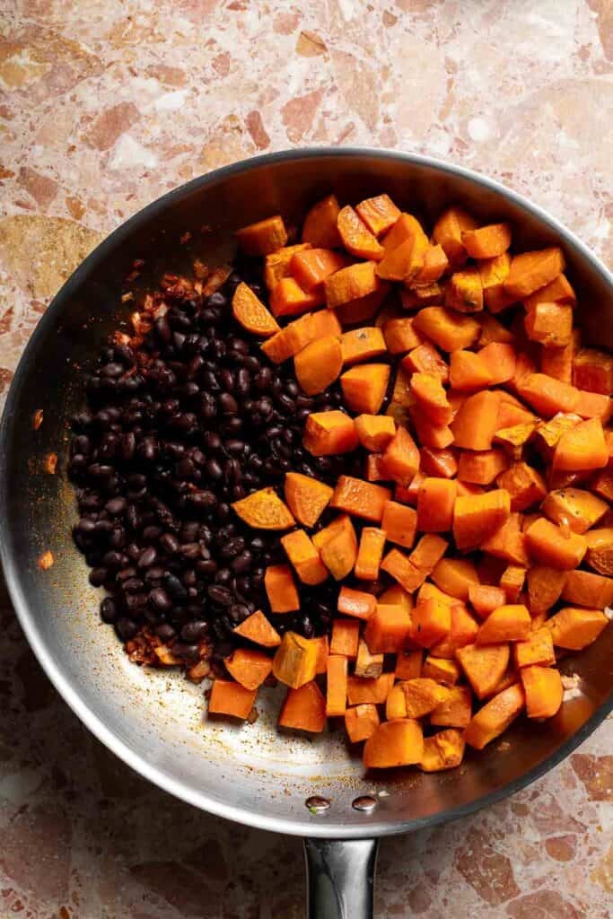 Roasted sweet potatoes and black beans added to the skillet of spiced onions.
