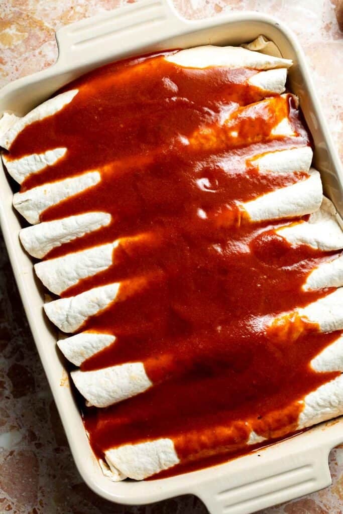 Enchiladas completely covered in red enchilada sauce.