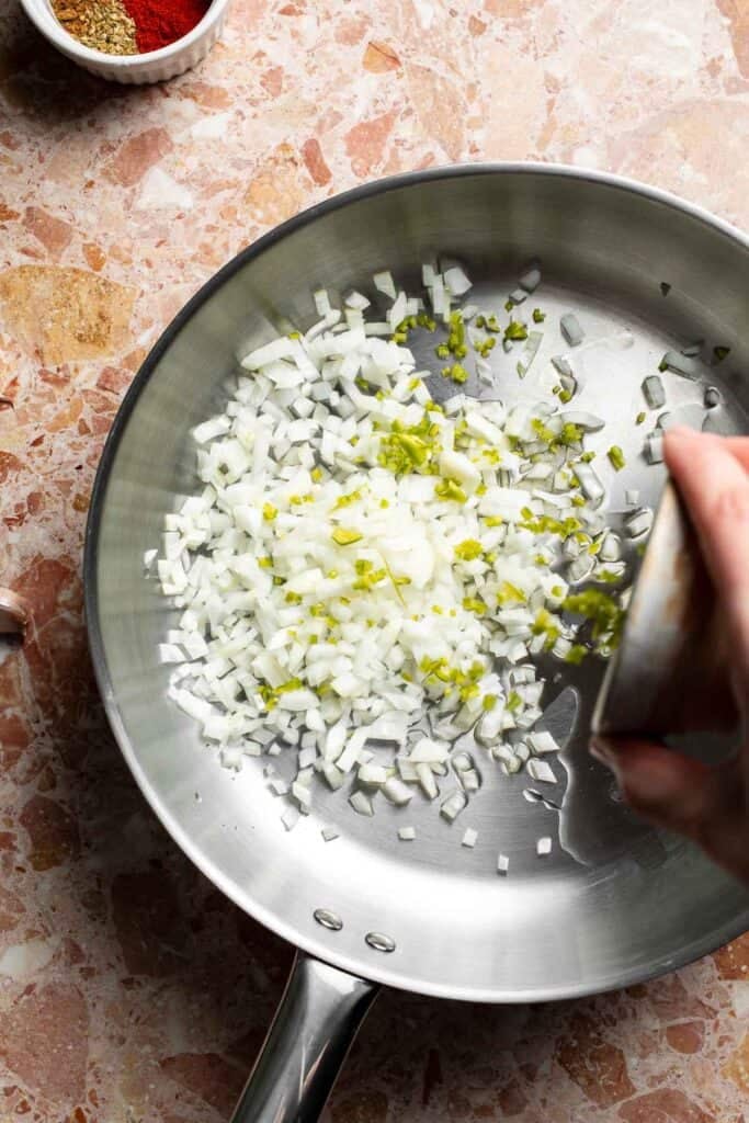 Diced onion and minced jalapeño added to the skillet.