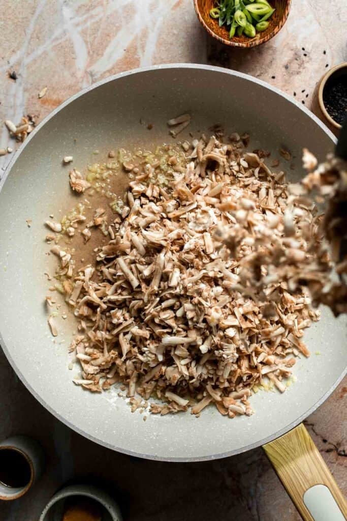 Shredded mushrooms added to the skillet.