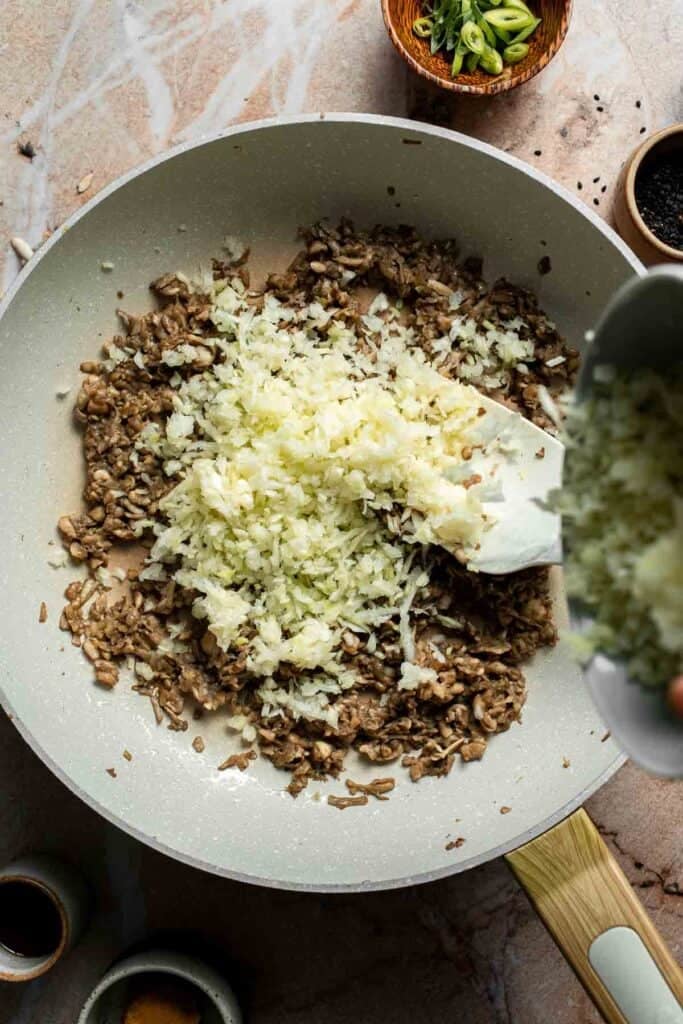 Finely shredded cabbage added to the mushrooms in the skillet.