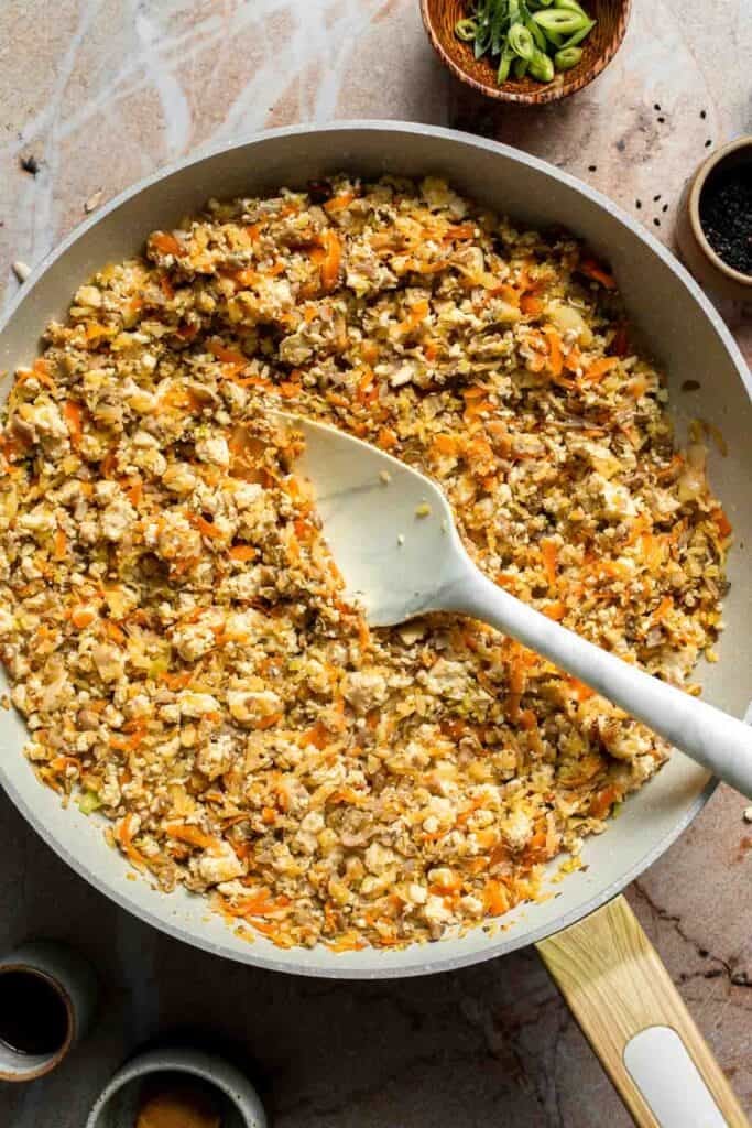 Tofu stirred into the vegetable filling in the skillet.